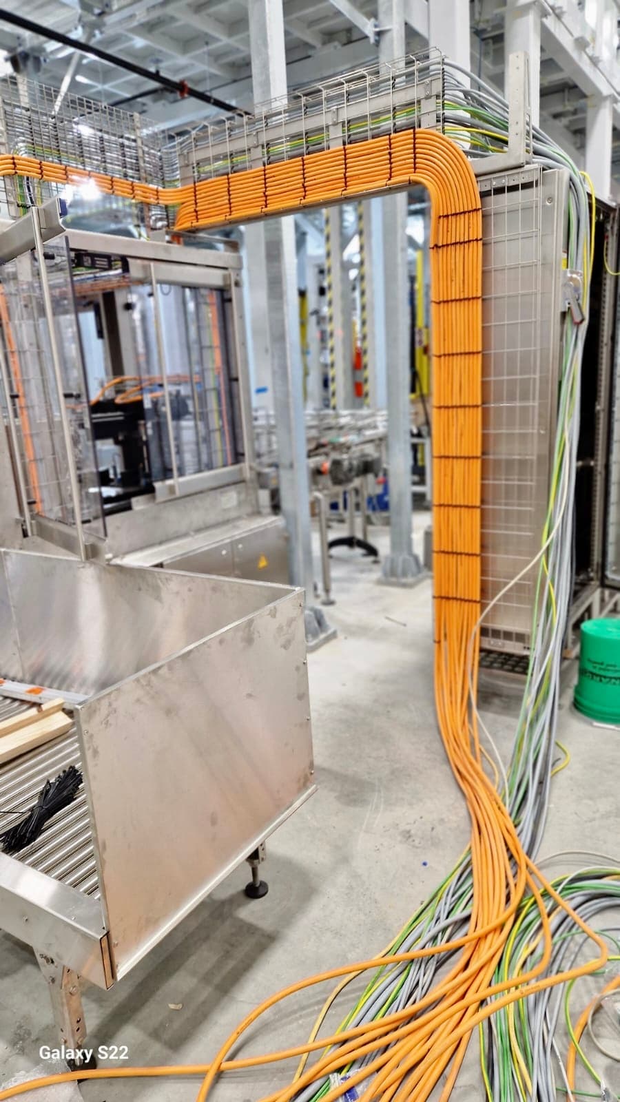Passerella industriale con cavi di potenza arancioni che scendono sull'impianto